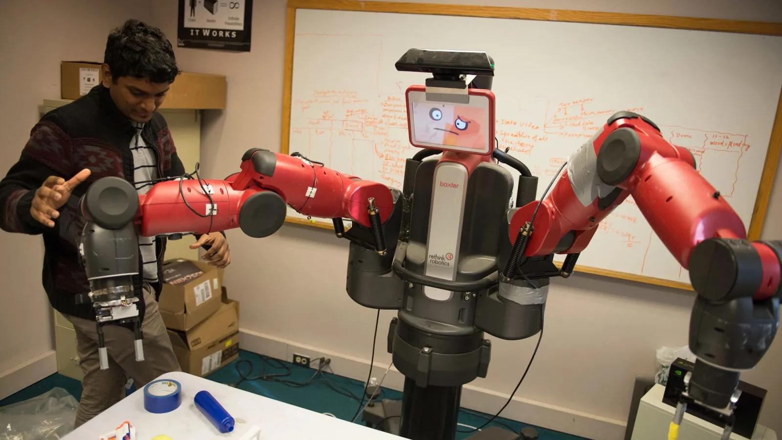PhD student adjusting a dual arm manipulator robot